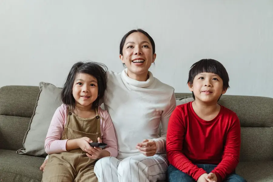 A mom laughing on the couch with her two kids